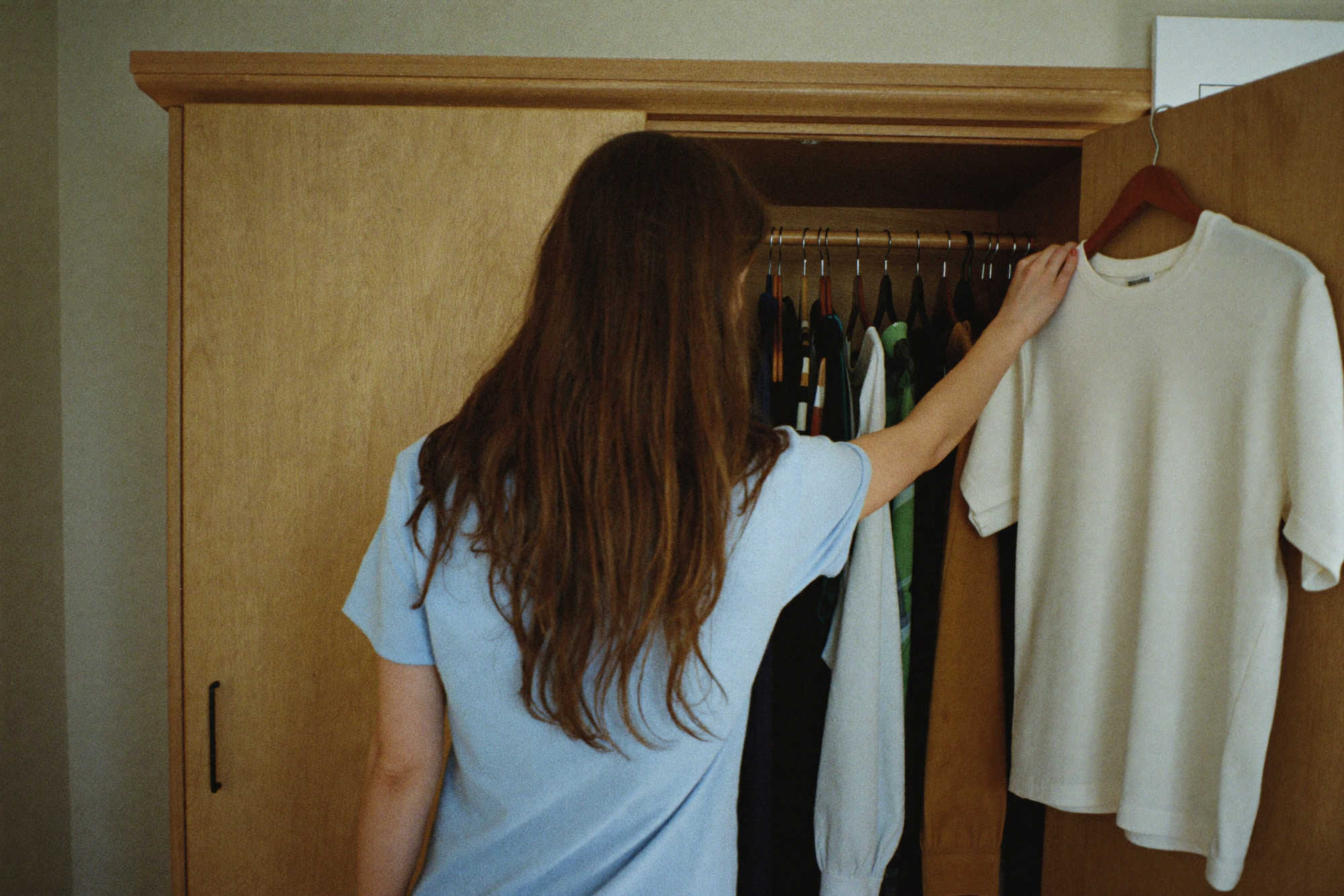 A woman standing before an open wardrobe, unable to choose