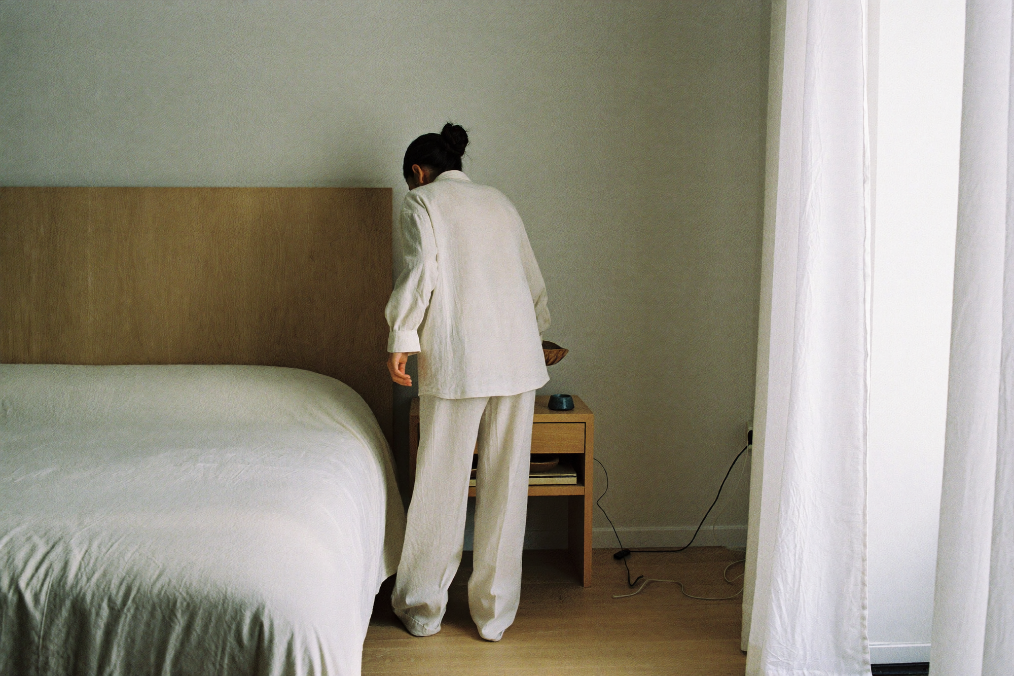A woman clearing the last object from her nightstand, leaving bare oak