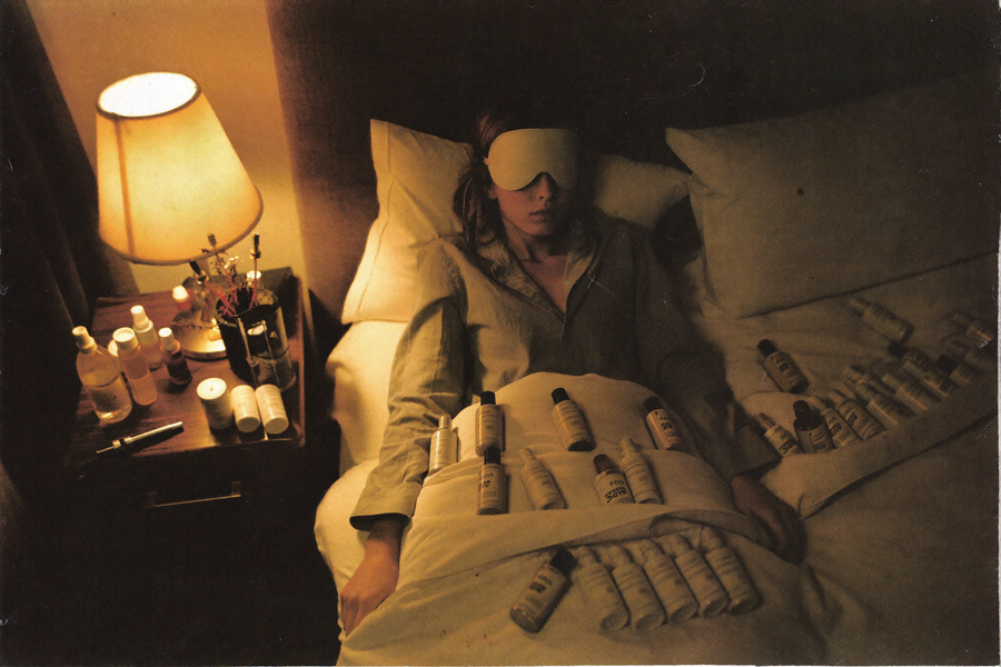 A woman in bed surrounded by too many sleep aids, more anxious than rested