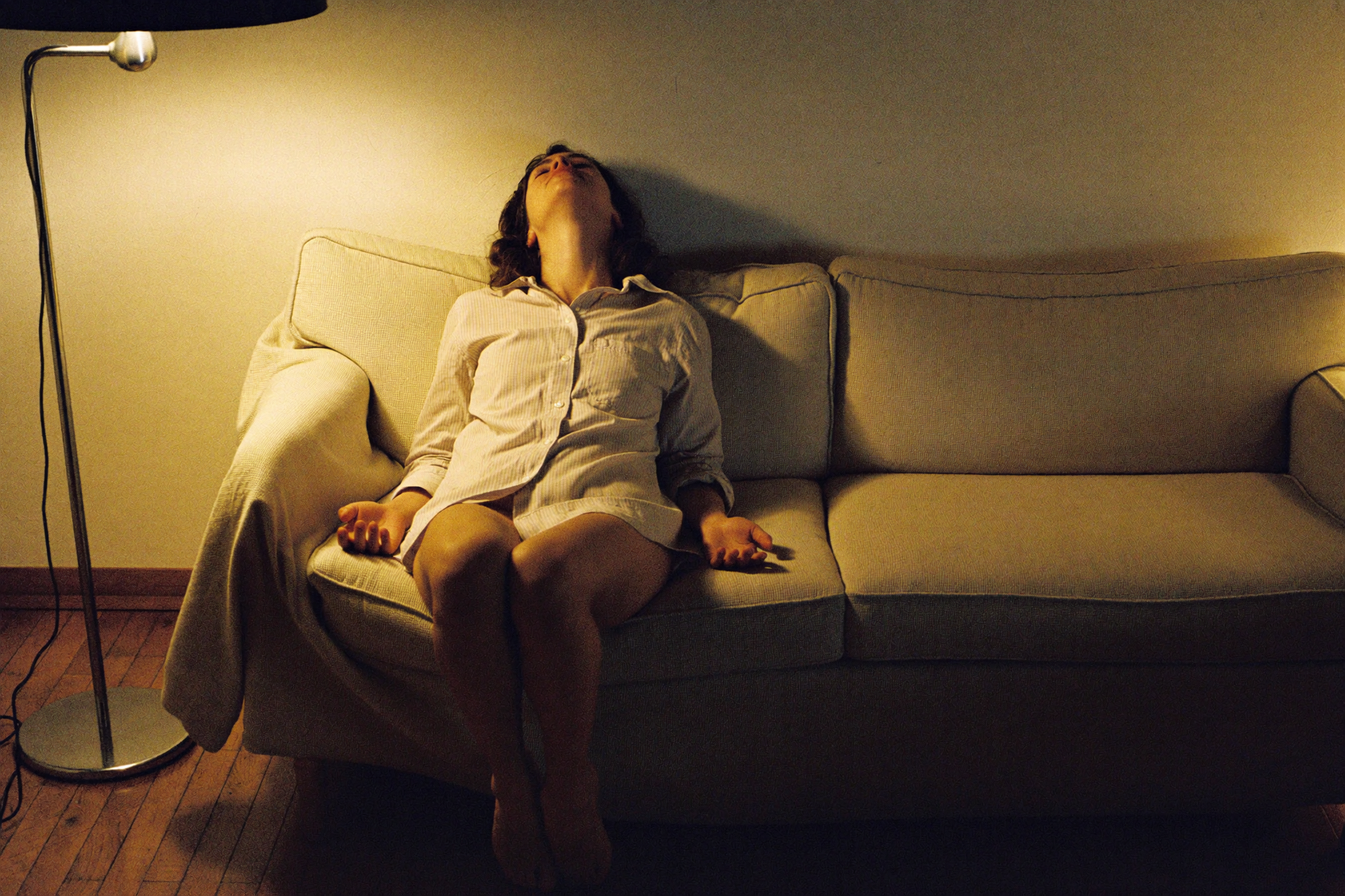A woman sitting back on a sofa in the evening, doing nothing at all