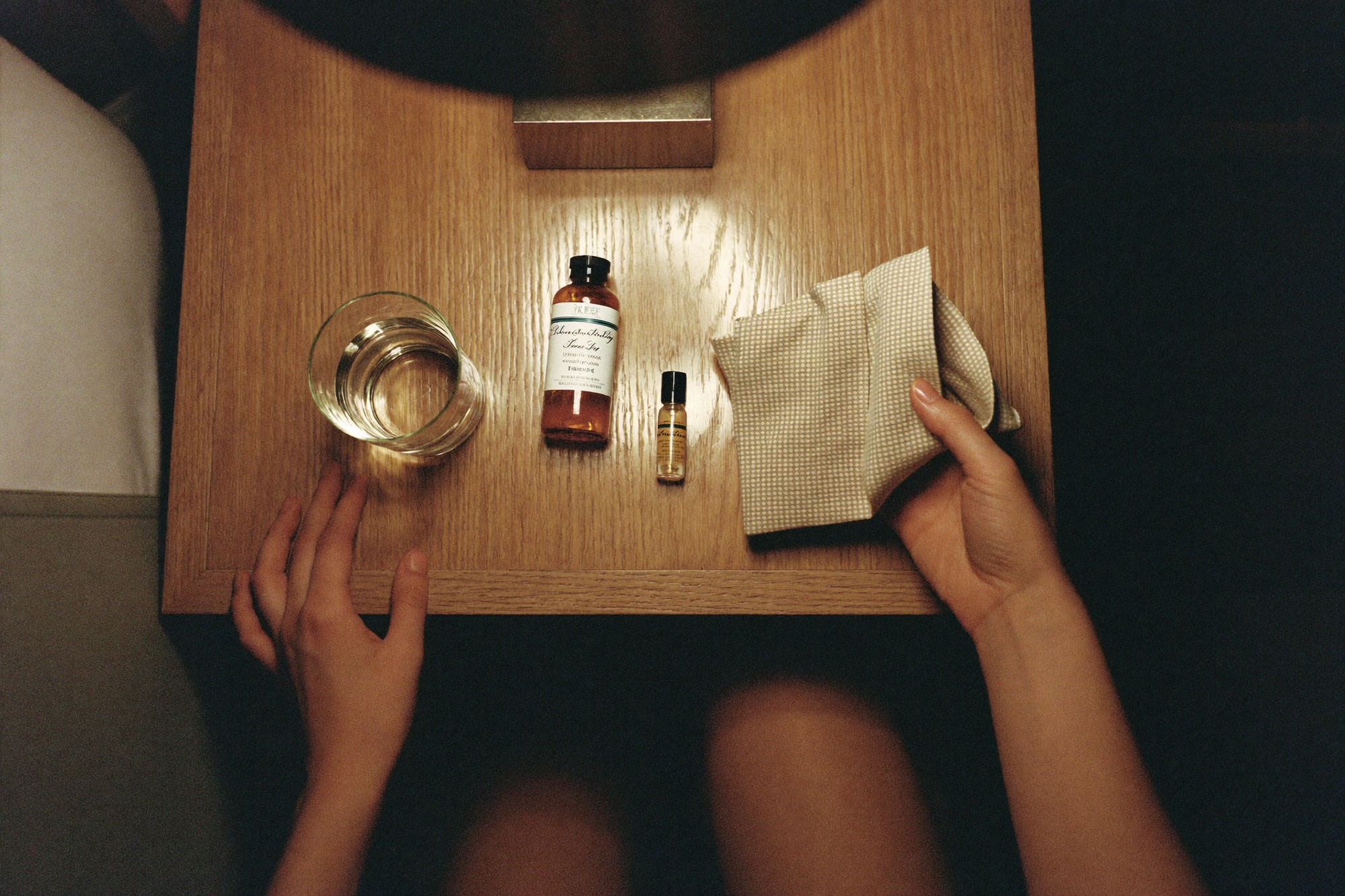 Two hands placing three simple objects in a row on a nightstand