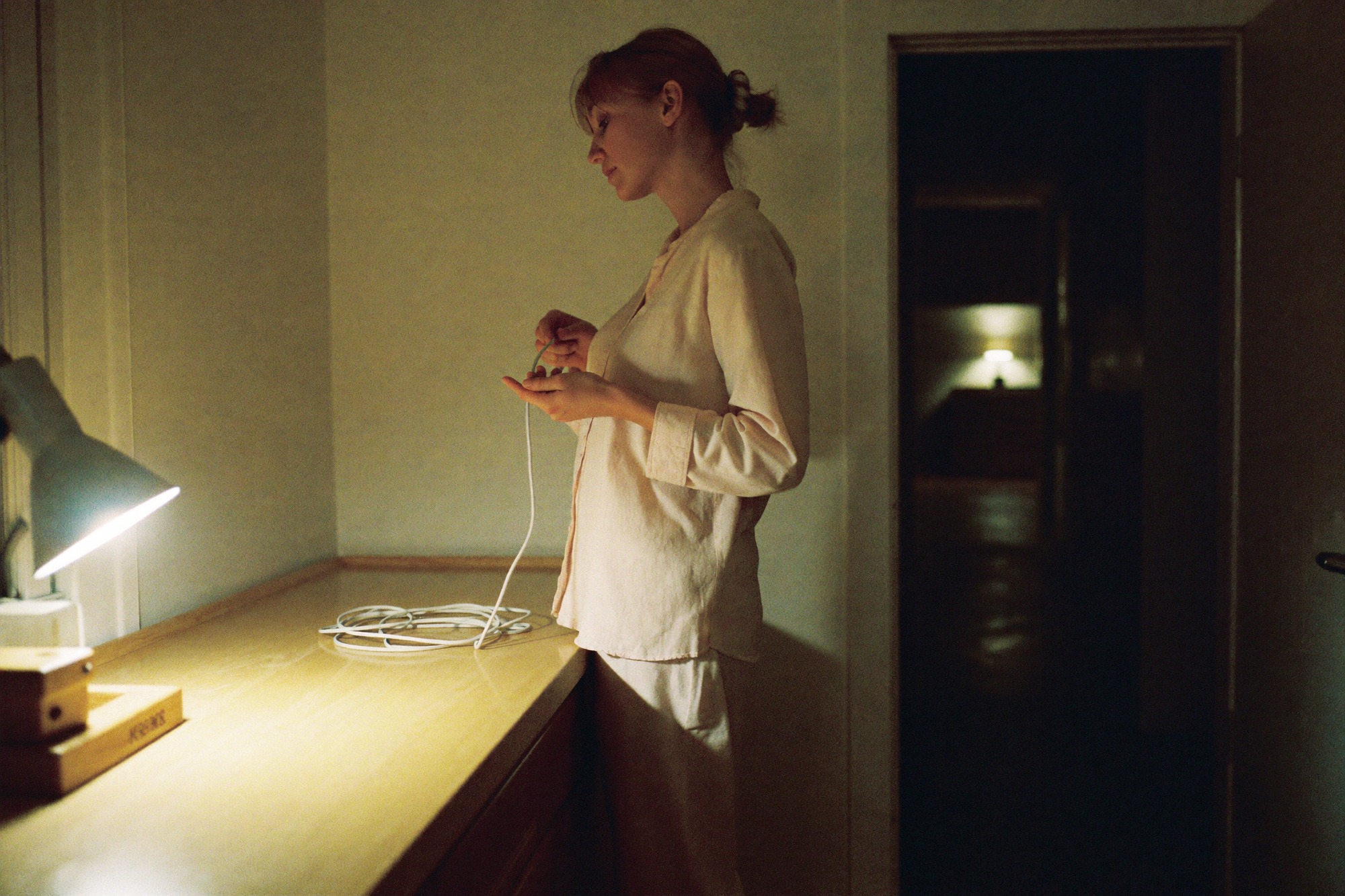 A woman leaving a coiled charging cable on a counter last thing at night