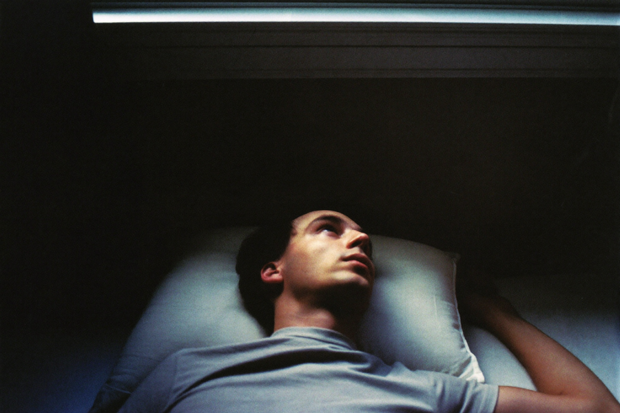 A man lying flat on his back at three in the morning, eyes open on the ceiling