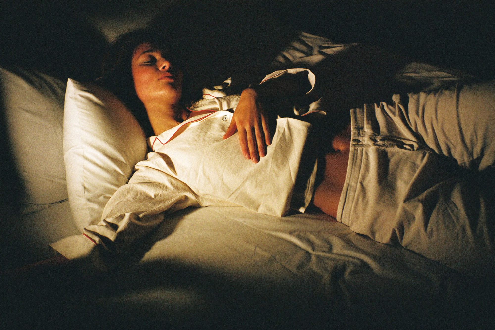 A woman lying on her back with one hand on her ribs, slowing her breathing