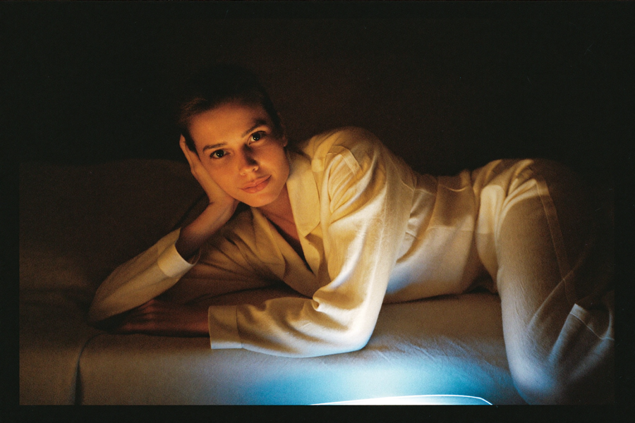 A woman in bed with her face lit cold blue in an otherwise warm dark room
