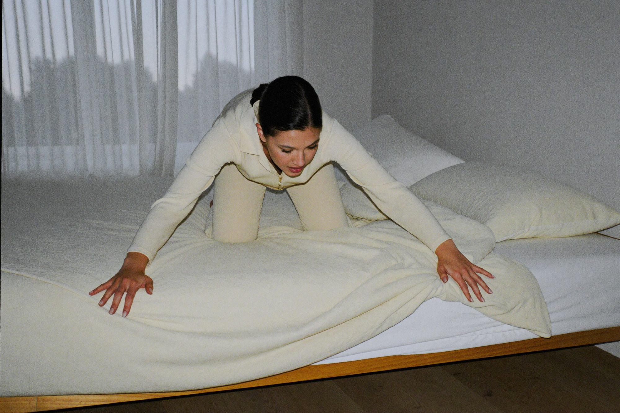 A woman making her bed with almost excessive precision very early in the morning