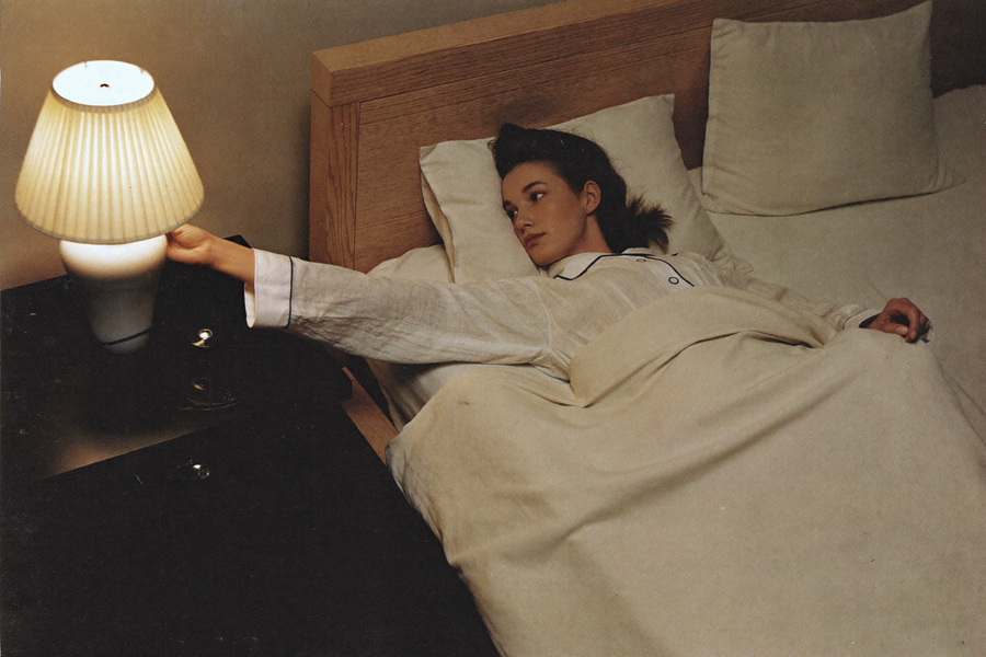 A woman reaching to switch off her bedside lamp earlier than she used to